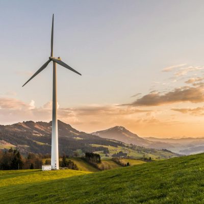 Photo by Pixabay Wind turbine amid rolling hills and mountains at sunset, symbolizing renewable energy and sustainability.